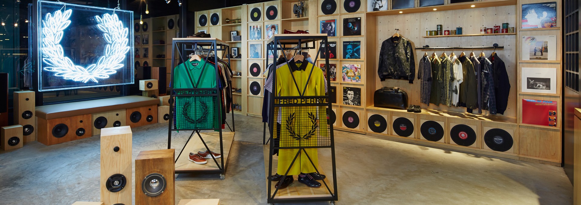 The Fred Perry Laurel Wreath Store in Singapore, designed by Studio Königshausen, pays homage to music and youth culture through its unique design. The exterior resembles a classic English shop front, while the window display resembles a vinyl record store with a Marantz vinyl player. Inside, a neon Laurel Wreath logo illuminates the space, and modular product walls house vinyl records alongside Fred Perry products for a distinct retail experience.